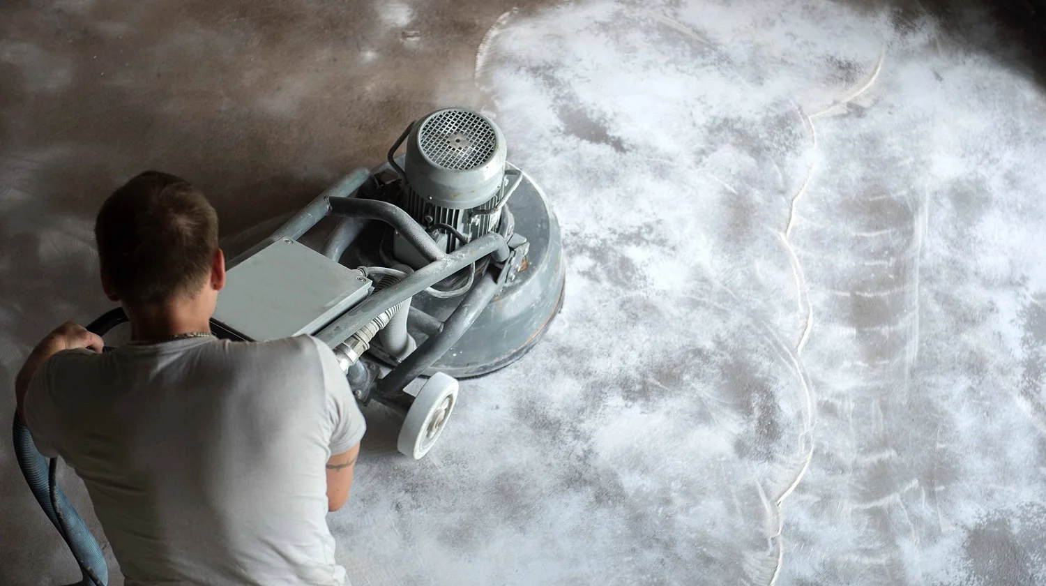 Construction worker in a family home living room that grind the concrete surface before applying epoxy flooring.Polyurethane and epoxy flooring.Concrete grinding.