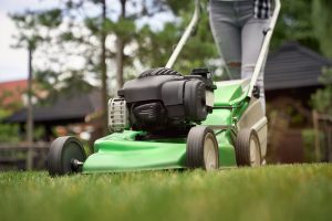 Close up of female legs of gardener using green lawn mower on backyard. Selective focus of woman working in summer, cutting grass in backyard. Concept of gardening, work, nature. Lawn Mower for St Augustine Grass Conclusion