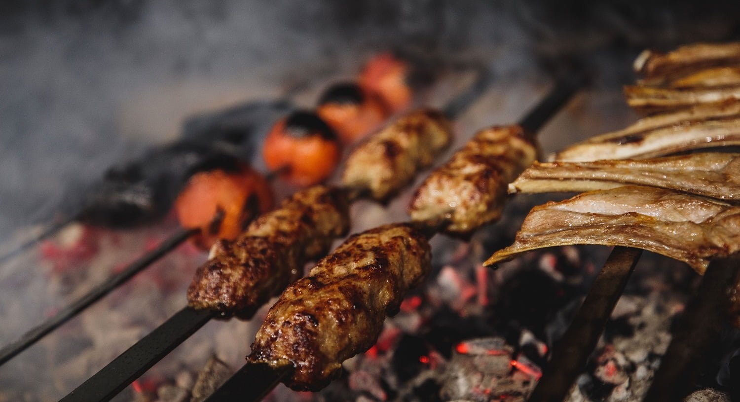 close up view of lula kebab on metal skewers on dark background