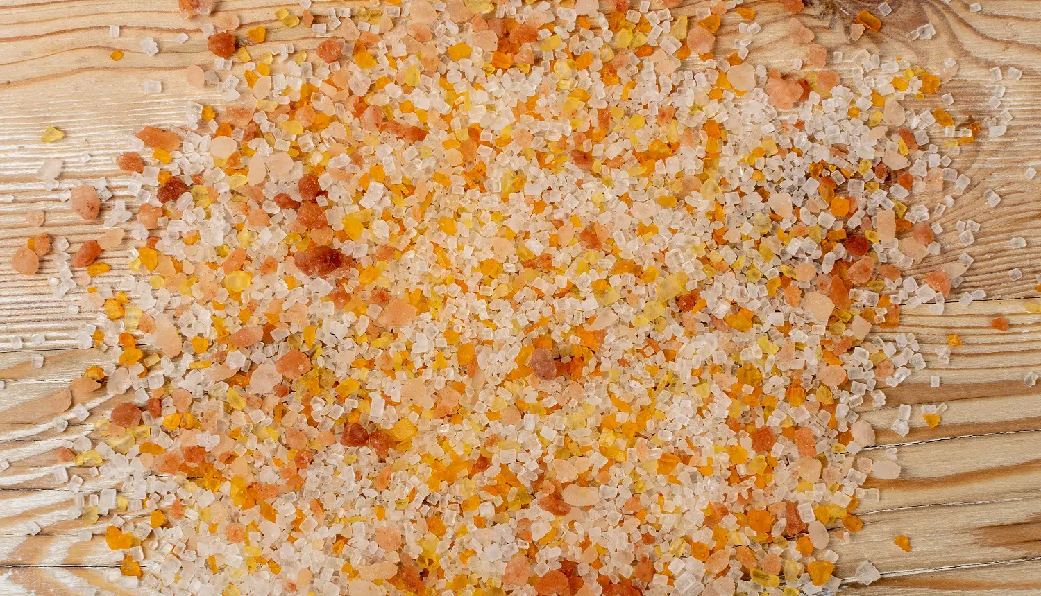 Colorful bath salts texture background top view. Aromatic orange salt crystals for body spa, bathing, beauty treatments, relaxation