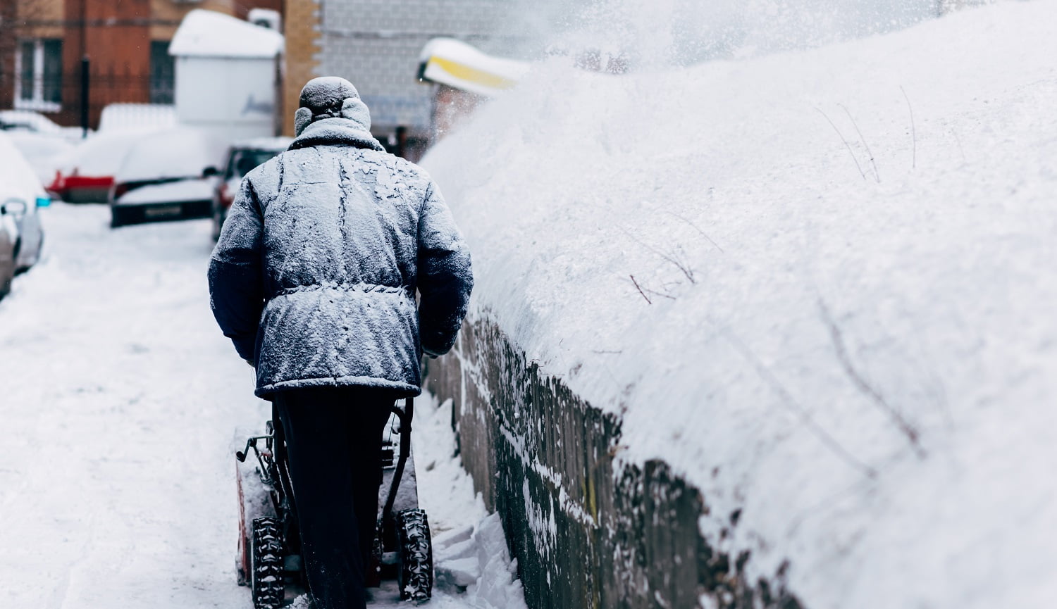 a man cleans up in the yard removes the snowthrower