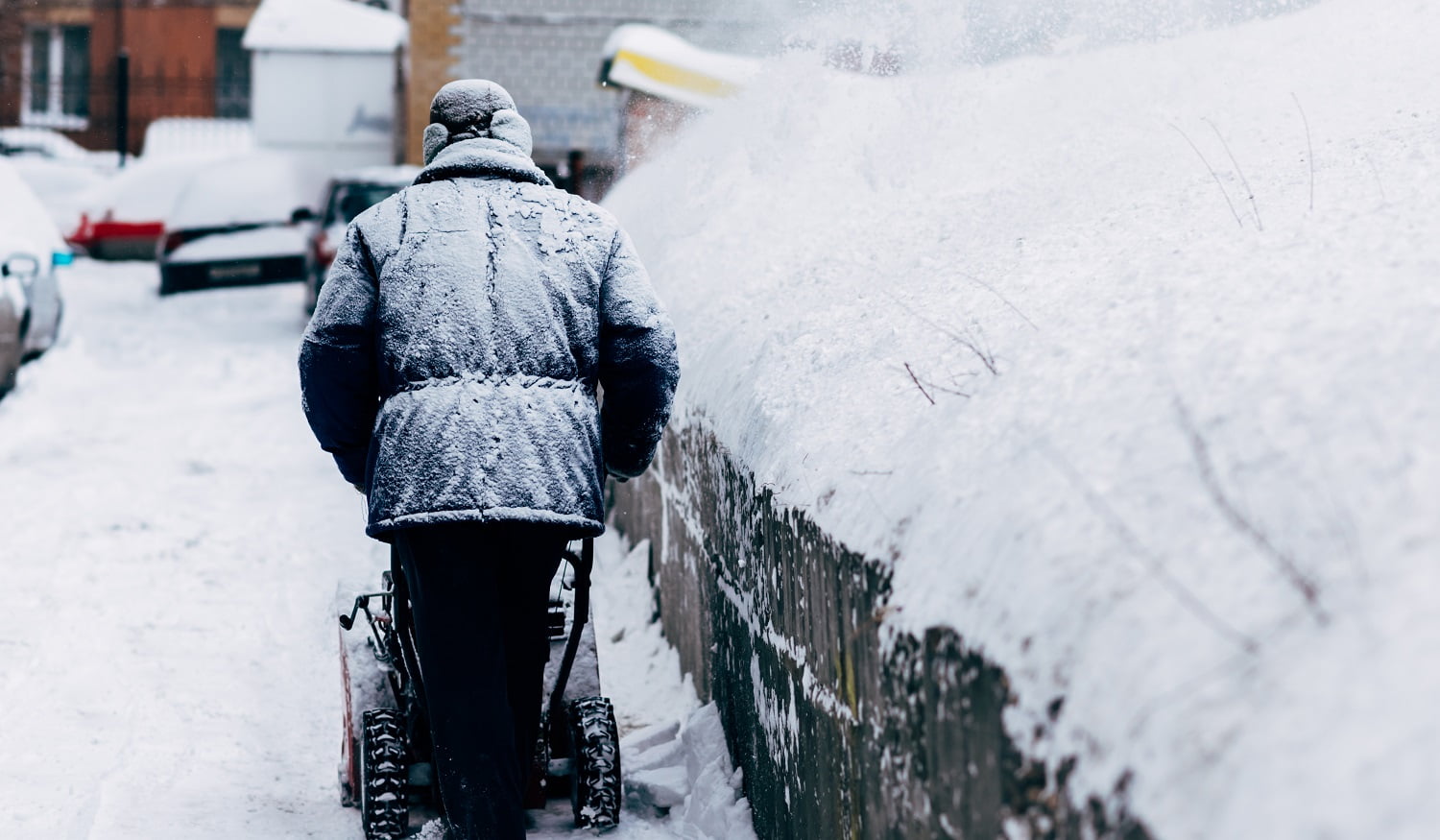 a man cleans up in the yard removes the snowthrower