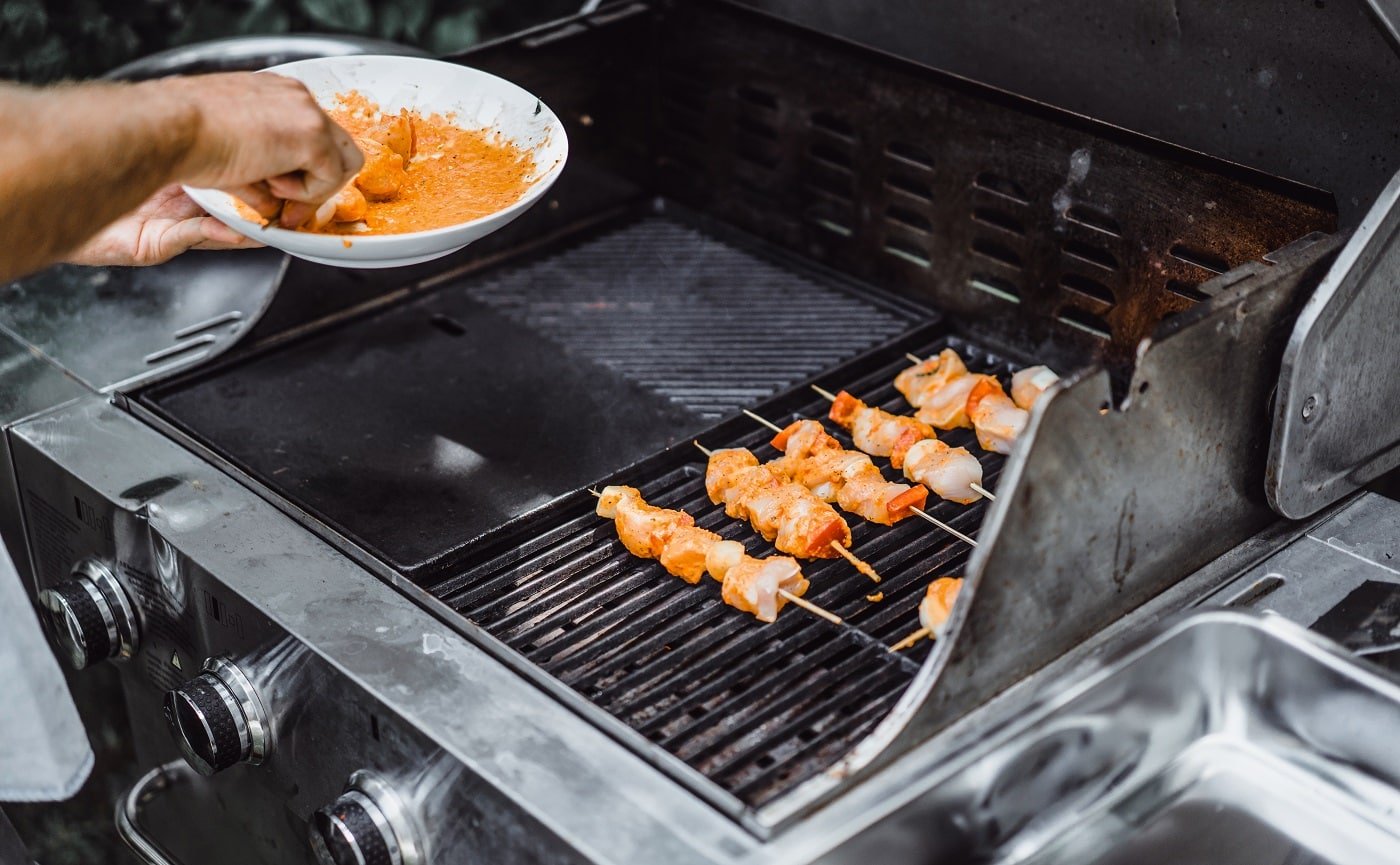 A man in tattoos makes barbecue grill meat outdoors.