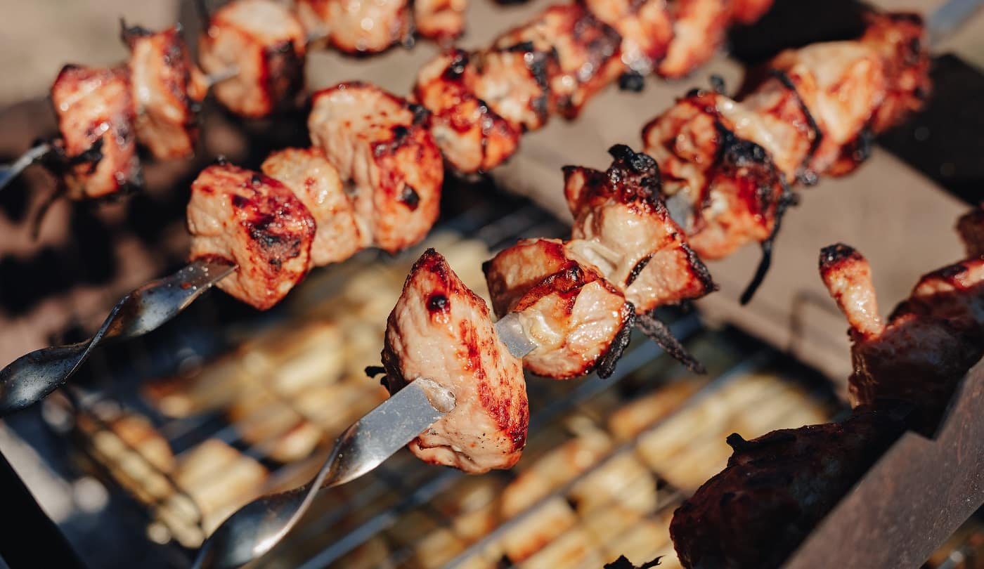 potatoes and grilled meat. fire and heat. cooking in nature on sunny day.