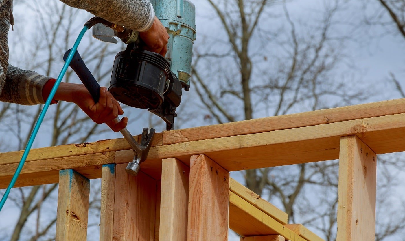 Authentic construction worker framing building contractor using nail gun