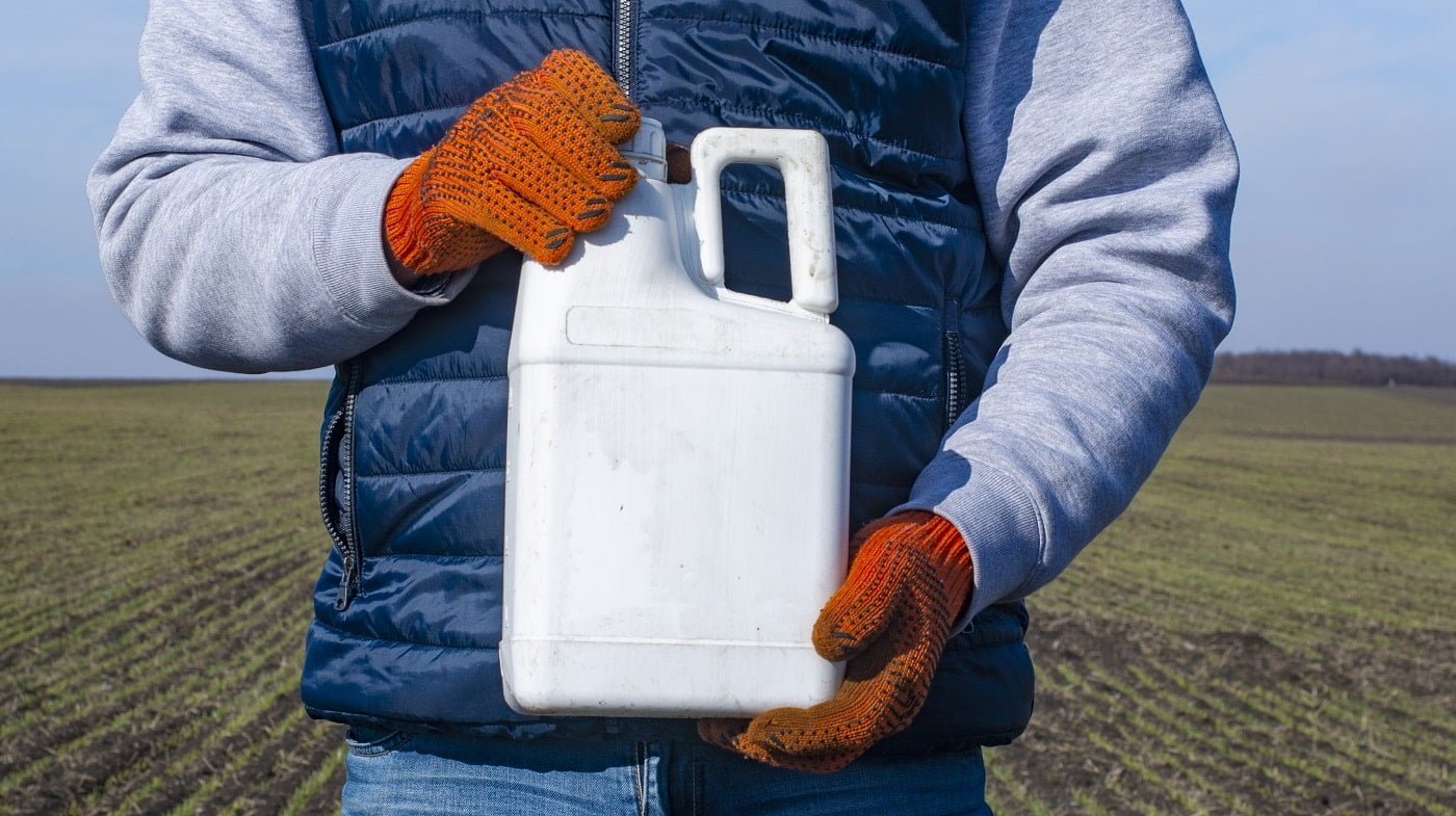 Protection of crops from pests and diseases. Bottle with a pesticide in the hand of an agronomist.