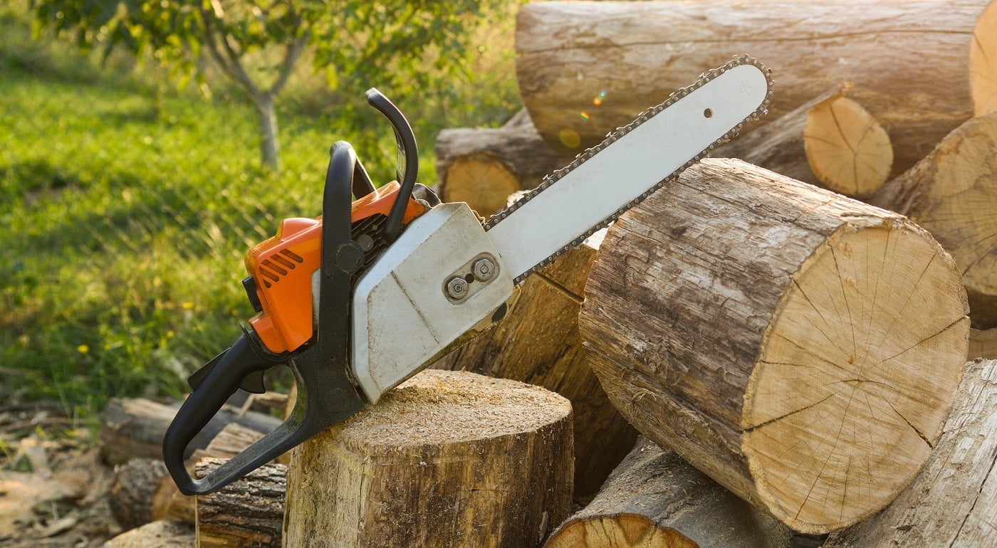 Close-up of woodcutter sawing chain saw in motion, sawdust fly to sides. A person using a chainsaw on pretty wood.Woodcutter saws tree with chainsaw on sawmill