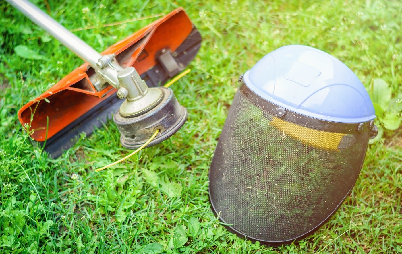 String trimmer and protective face mask on grass