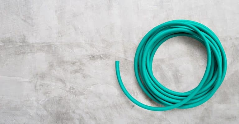 Green garden hose on concrete background. Copy space