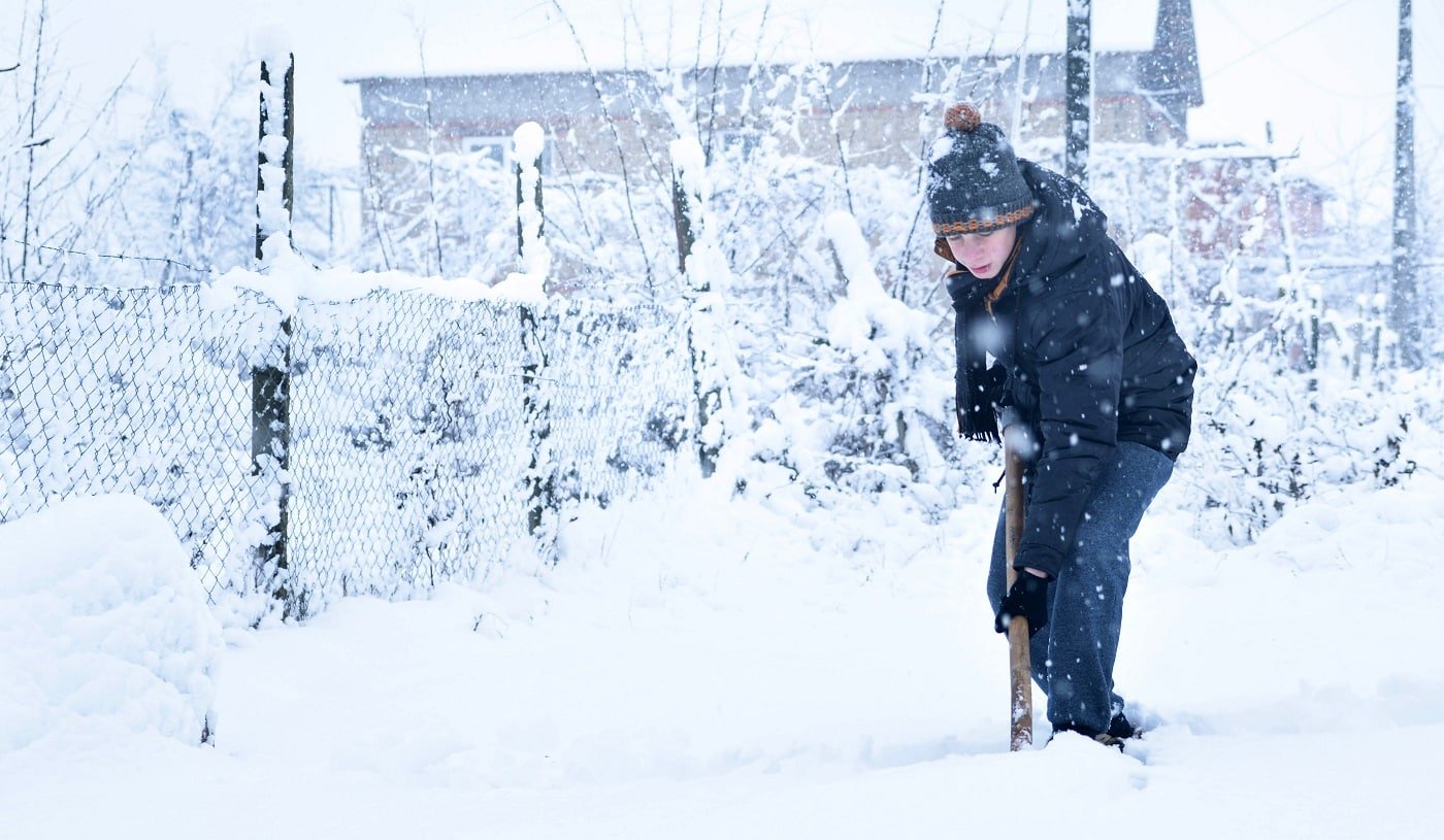 Teenager removing snow with a shovel in the winter