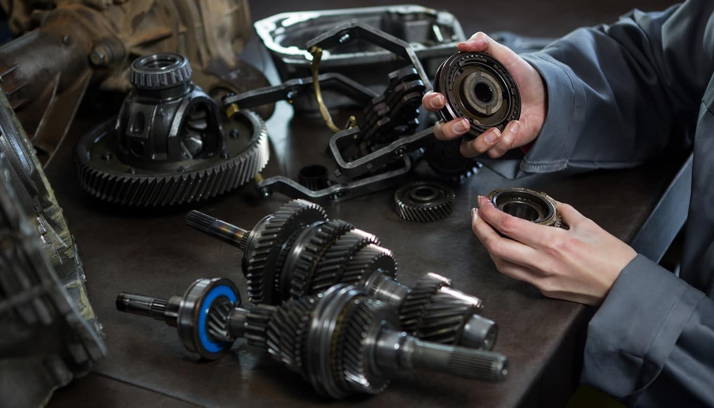 Close-up of female mechanic holding spare parts of car at repair garage