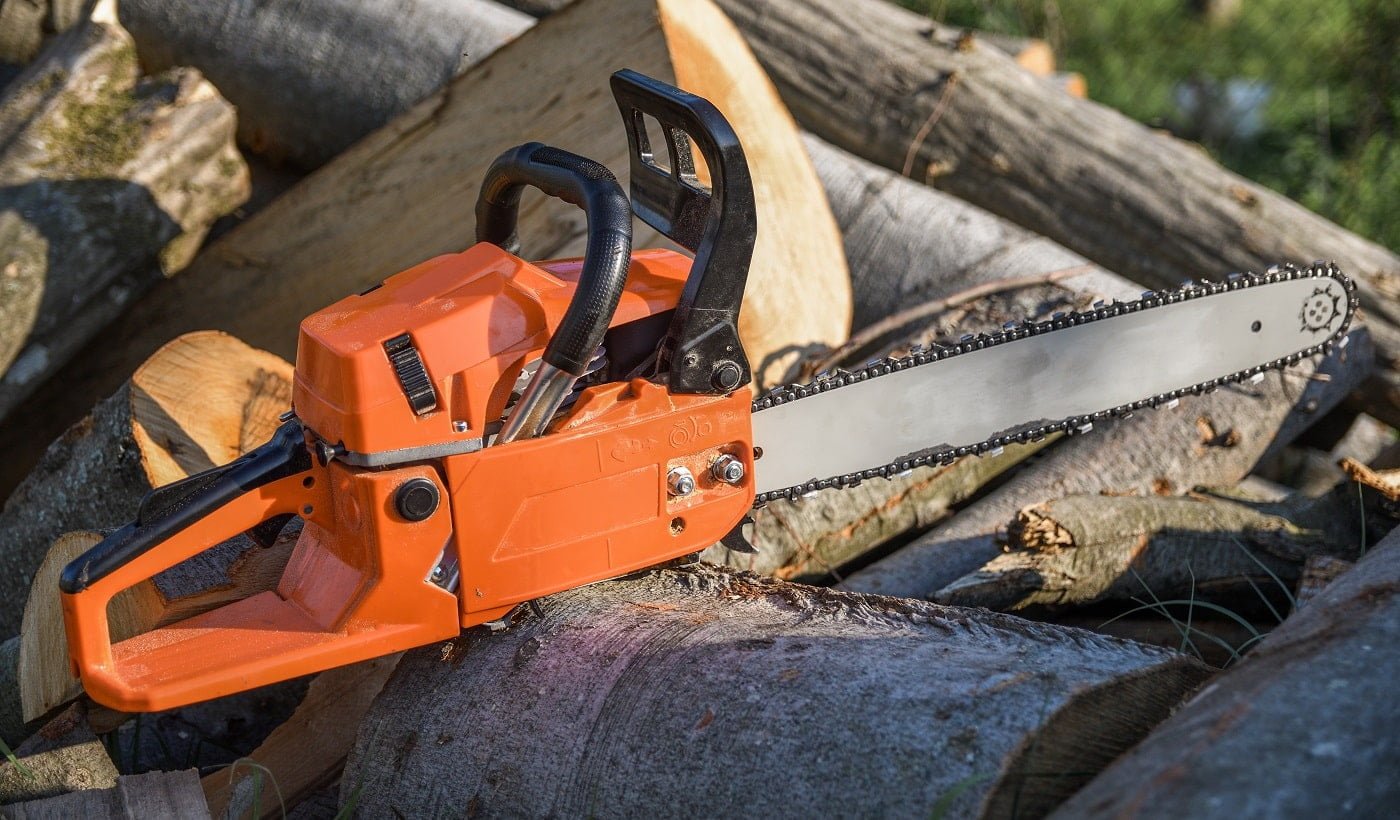 Chainsaw that stands on a heap of firewood in the yard on a background of firewood and trees cut by a chainsaw.