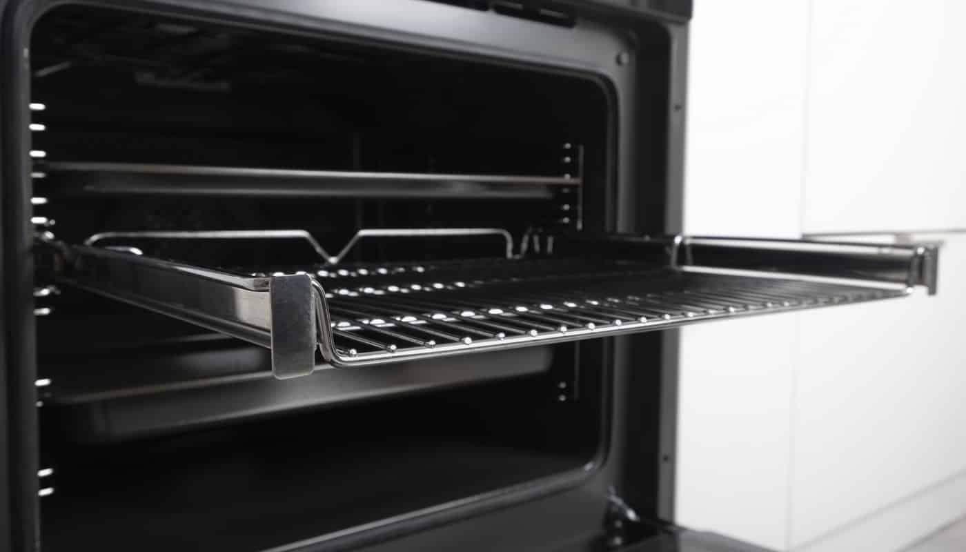 New modern electric oven built in black with screen, convention and grill, empty and open. Telescopic guides. Scandinavian style in a white minimalistic kitchen. High quality photo