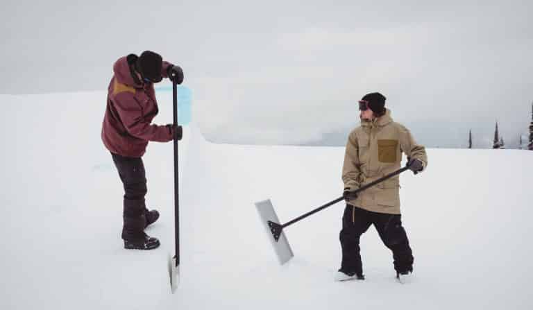 Two men cleaning snow in ski resort during winter