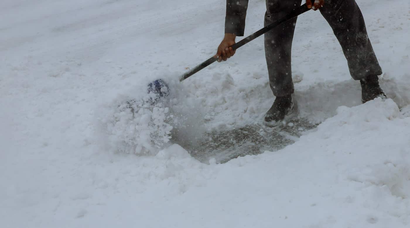 Workers sweep snow from road in winter, Cleaning road from snow storm. Man Removing Snow with a Shovel