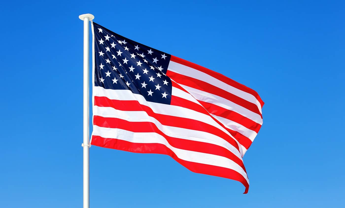 American flag waving in blue sky. Solar Powered Flagpole Light.
