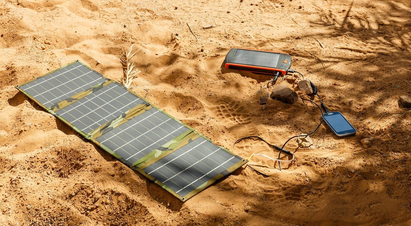 solar panel lying on the ground and charges the smart phone, the Sahara desert. Charge smart phone from the solar battery.