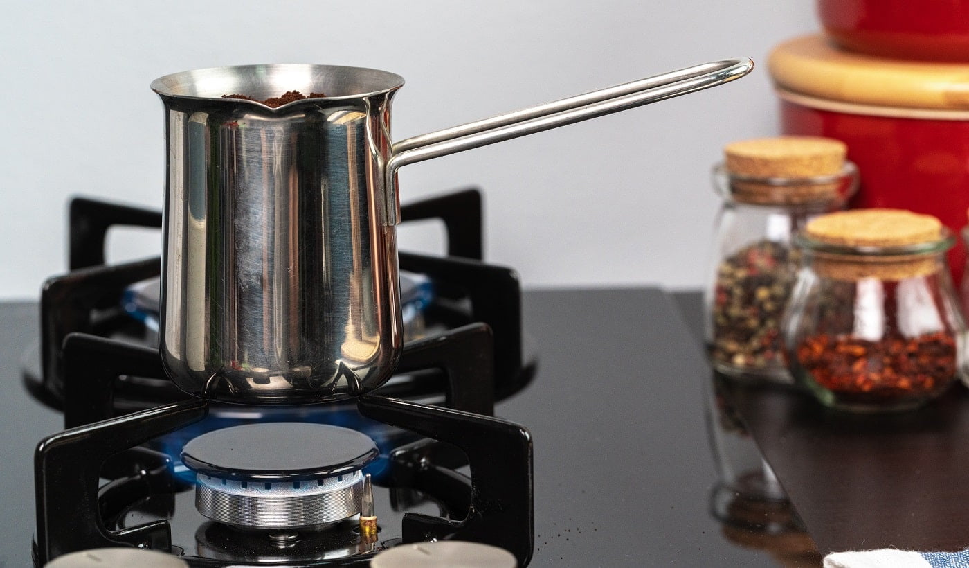 Brew coffee in a steel turk on a gas stove close up