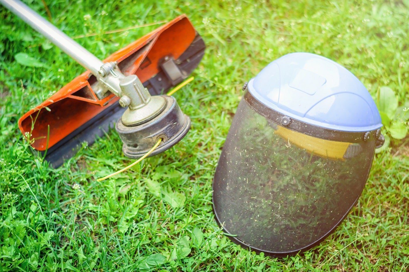 String trimmer and protective face mask on grass