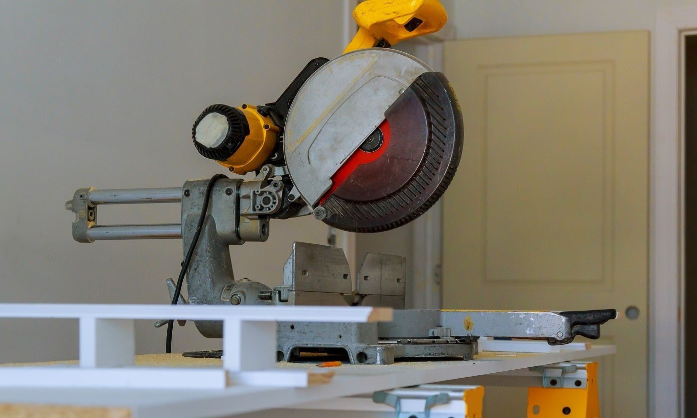 contractor uses a circular saw to cut trim molding Miter Saw on a construction site with a worker in background. 12-Inch Miter Saws.