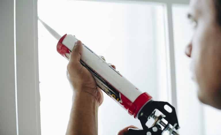 Man using a silicone gun to repair a window