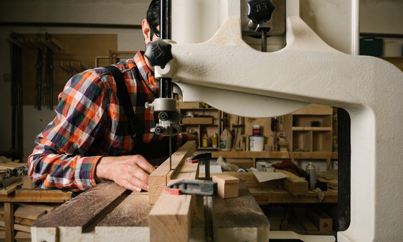 Working process in the carpentry workshop.A man in overalls works on a band saw in a carpentry workshop.Profession, carpentry, woodwork and people concept