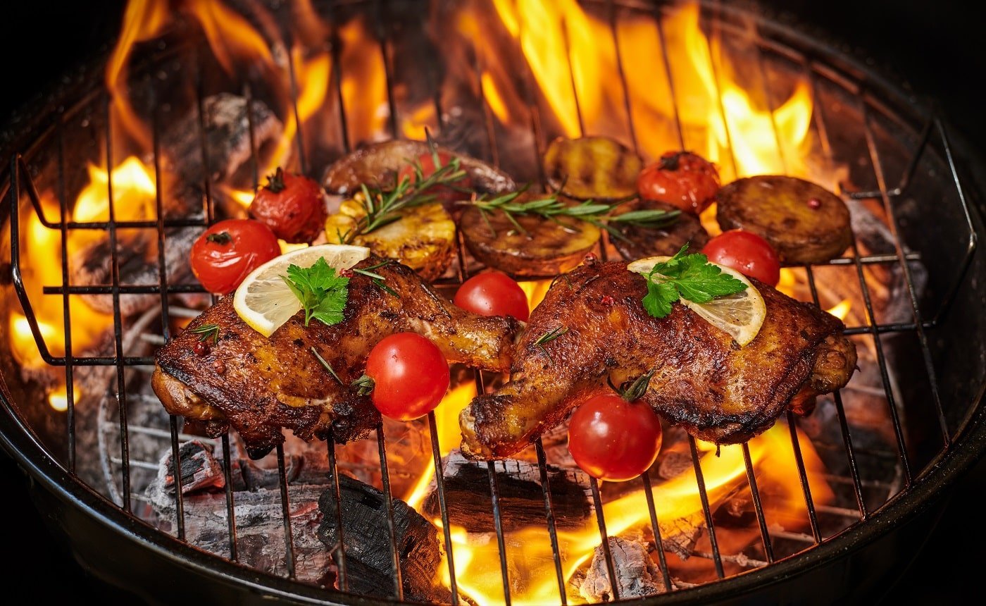 Grilled chicken legs on the flaming grill with grilled vegetables with tomatoes, potatoes, pepper seeds, salt. top view with copy space. tasty snack. flat lay. healthy lunch menu. diet food.