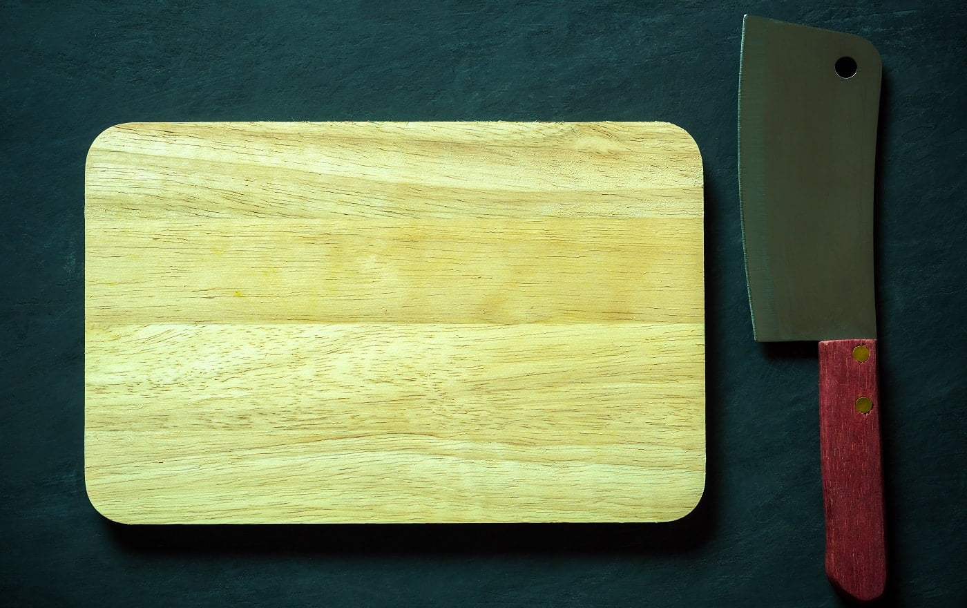 Wooden cutting board and Chinese chef knife on black cement floor. Top view and copy space for text. Concept of kitchenware and cooking.