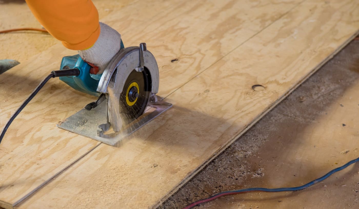 Man cutting plywood using an electrical chain saw professional tools