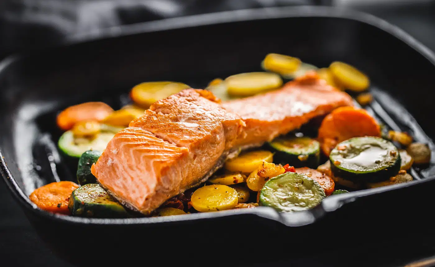 Tasty grilled salmon with vegetables served on grill pan.