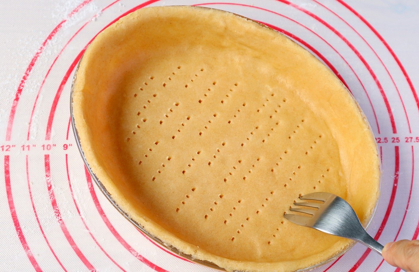 Using fork to poke the holes all over the dough before blind baking homemade pie crust