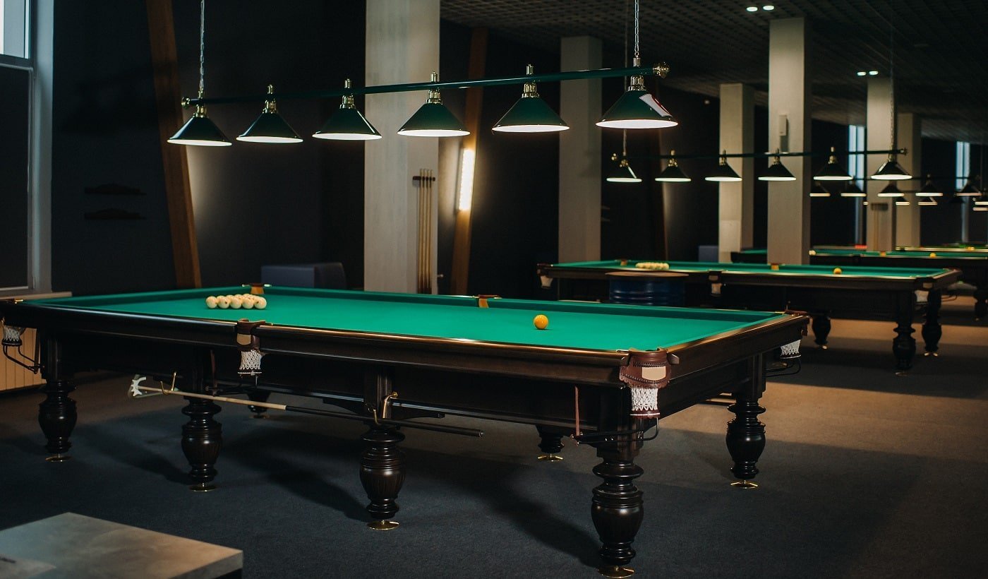 there are a lot of billiard tables with green surfaces and balls in the billiard club.