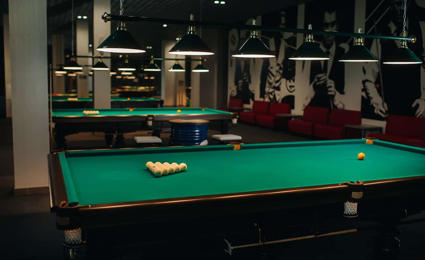 there are a lot of billiard tables with green surfaces and balls in the billiard club.