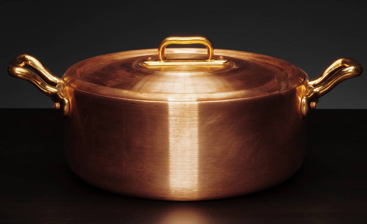 Shiny vintage copper cookware over dark background