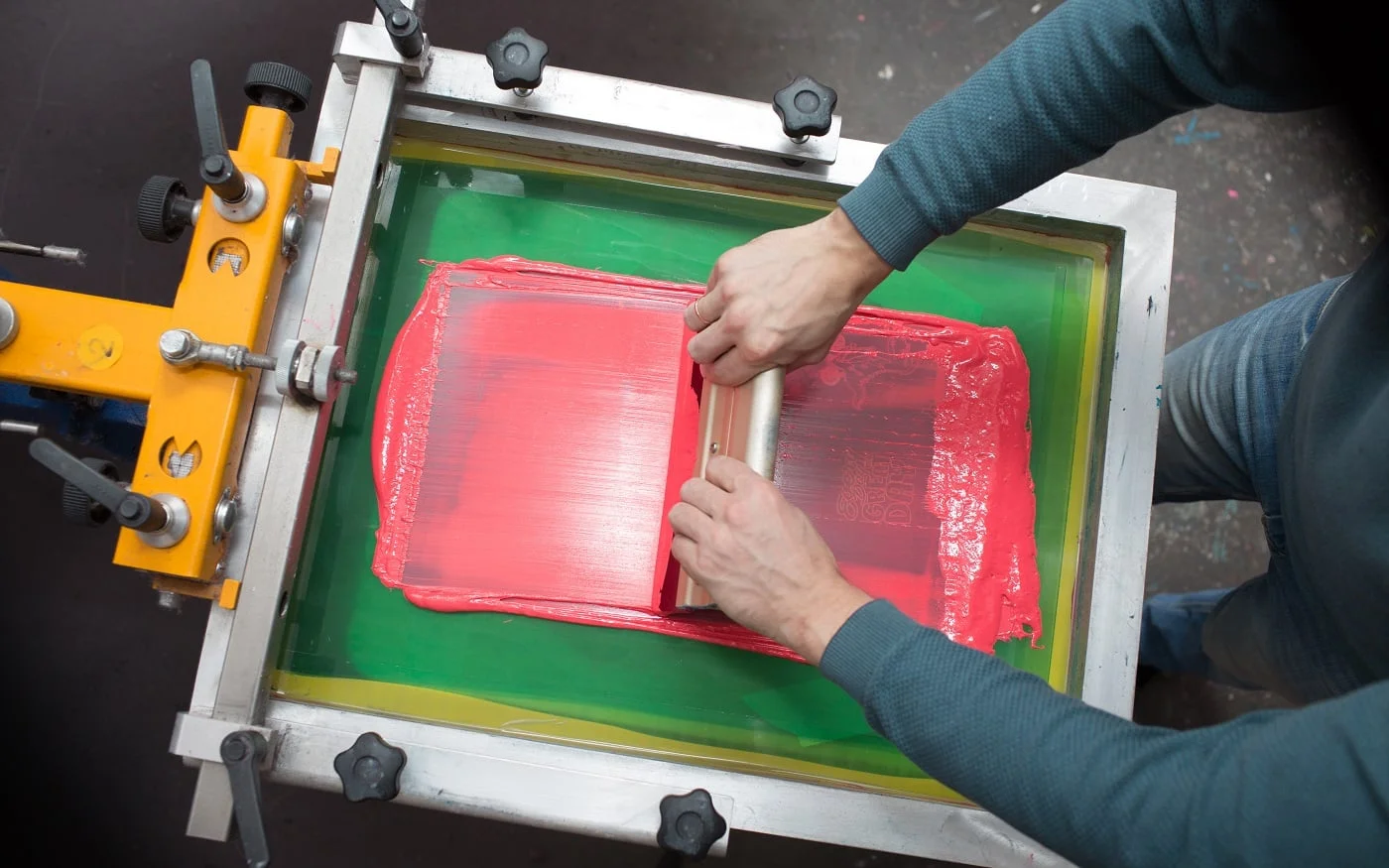 Silk screen printing. Serigraphy. Color paints and fabric. Plastisol paint and squeegee.