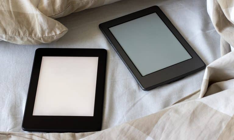 Two modern electronic books with a blank screens on a white and beige bed. Mockup tablets on bedding