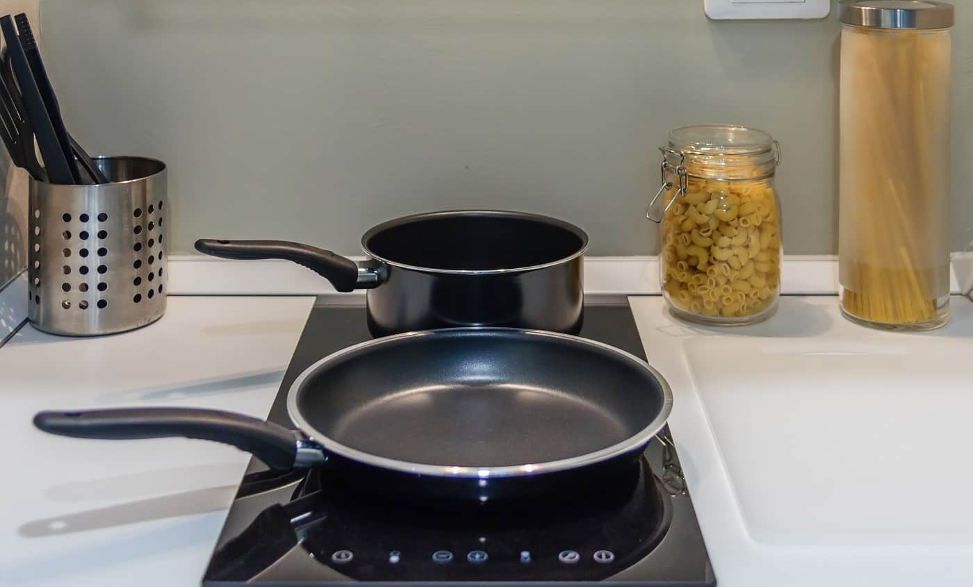 Black pan on Induction stove top panel in modern kitchen for cooking, closeup