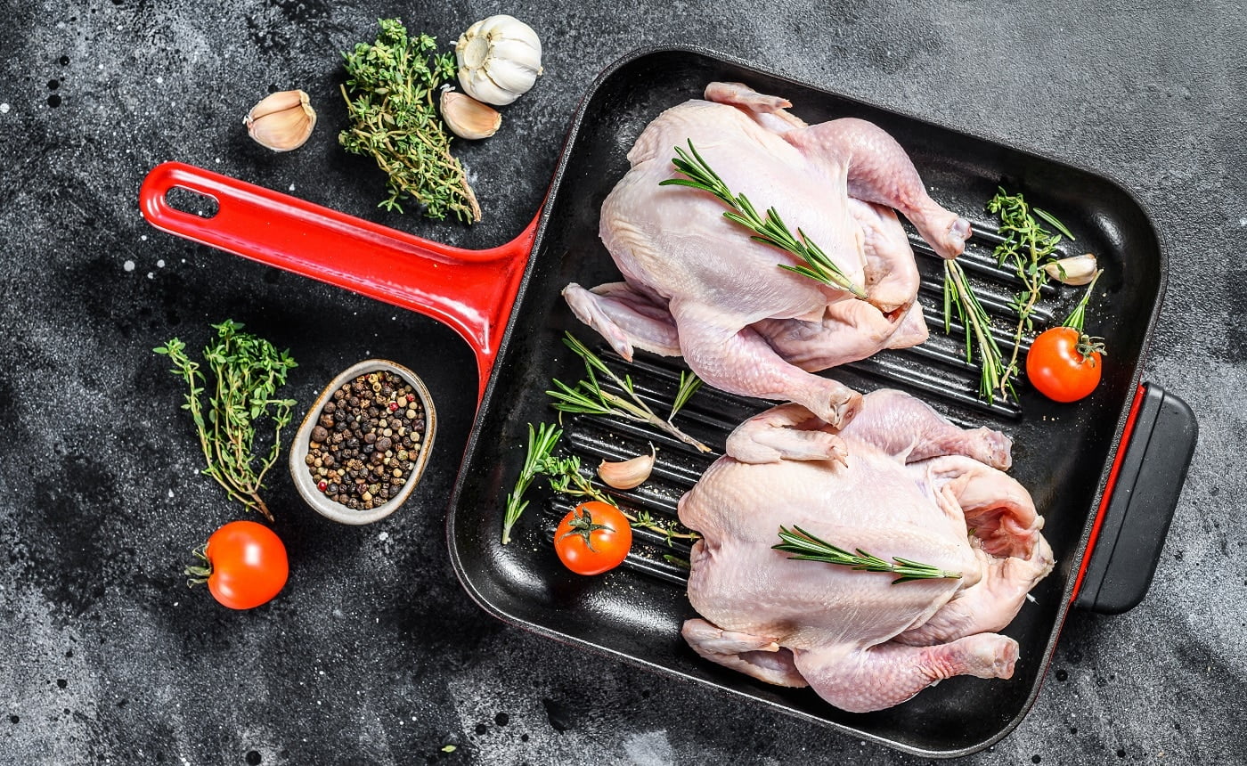 Organic farm raw whole chicken in a pan. Black background. Top view.