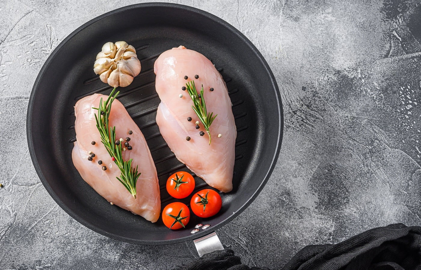 Raw organic chicken breastin grill pan on a grey background. Food preparation, top view