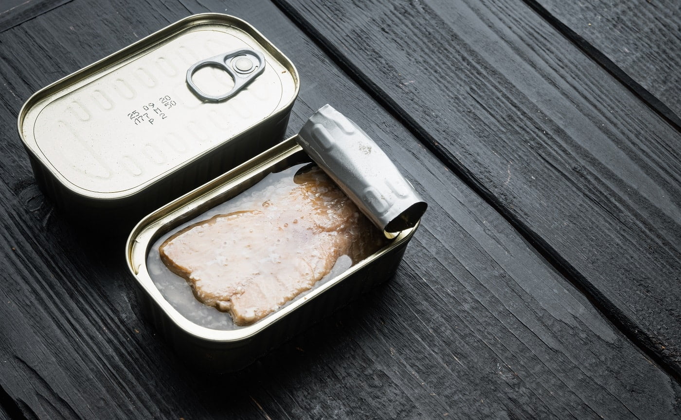 Canned Wild Alaska Salmon set, in tin can, on black wooden table background, with copyspace and space for text