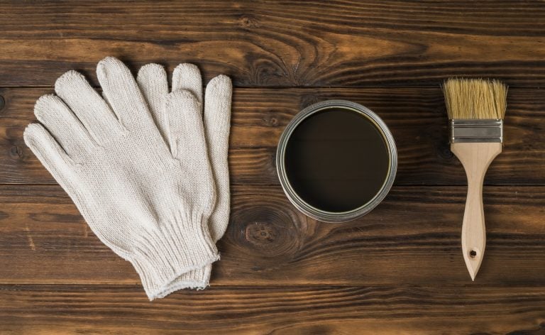 Brush, gloves and jar with a protective coating for wood on a wooden background. The rendering of wood.