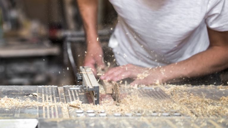 a man working with wood product on the machine, closeup