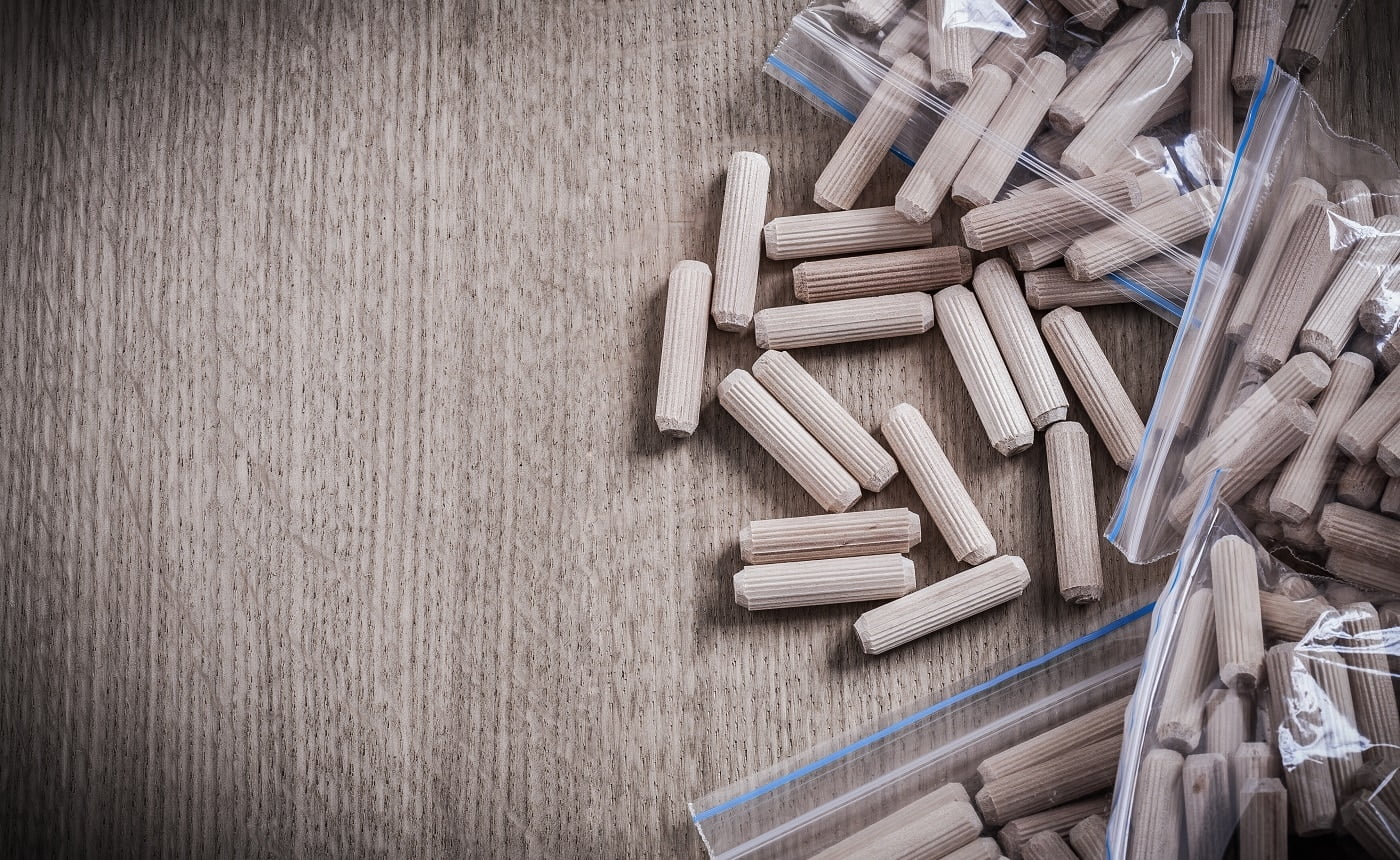 Woodworking dowels on wooden board copy space construction concept.