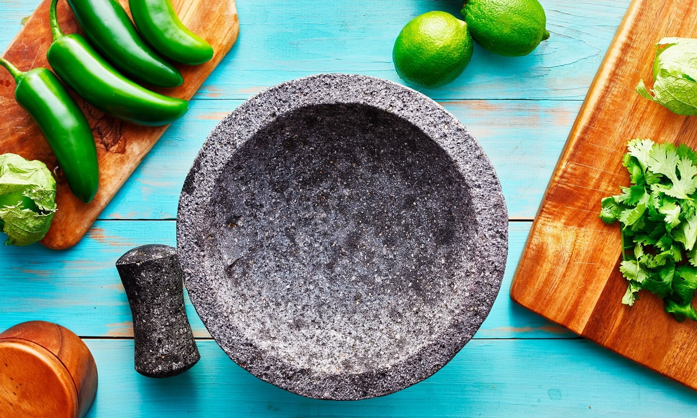 empty molcajete on table with ingredients ready to prep