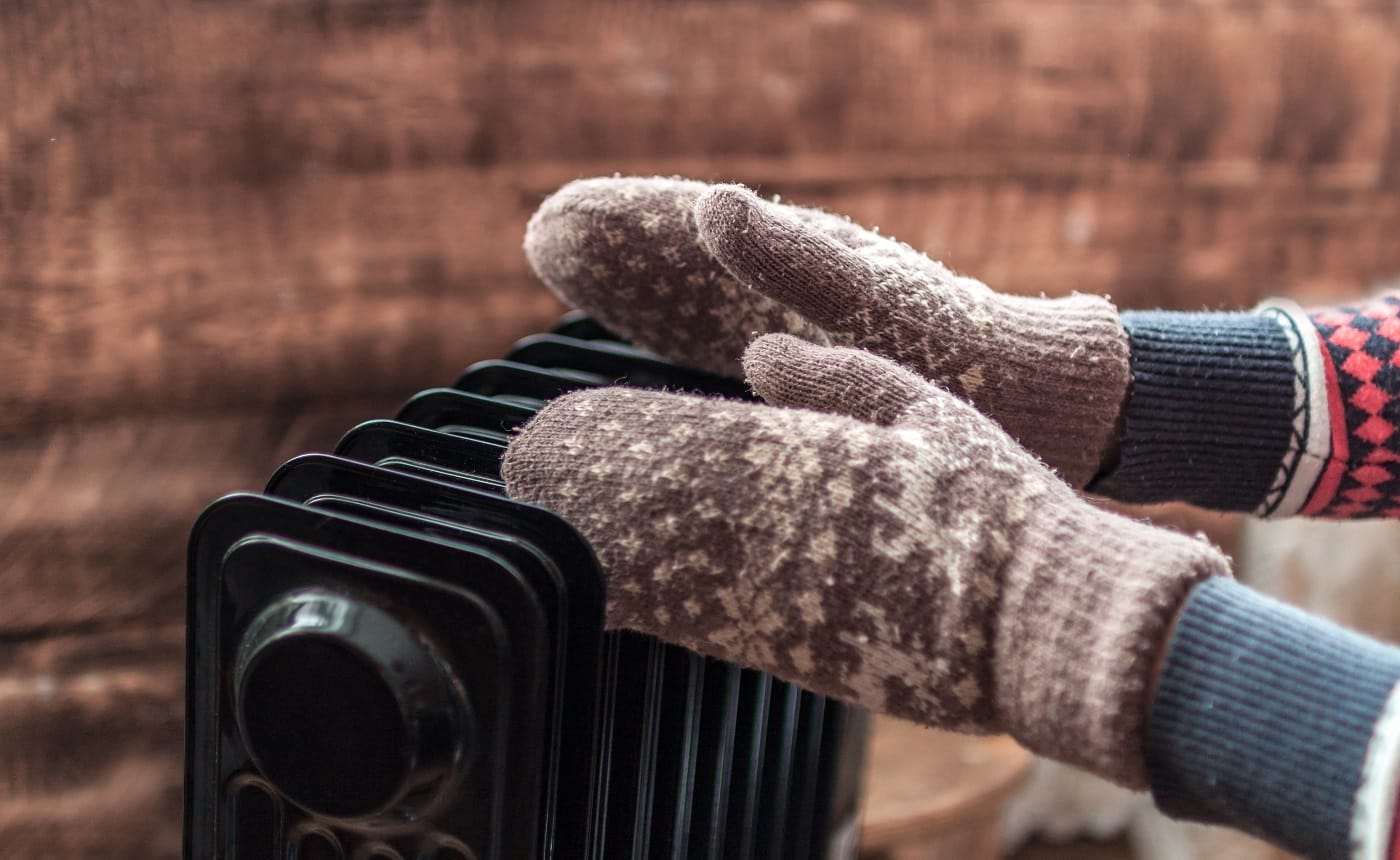 Women's hands in Christmas, warm, winter mittens on the heater. Keep warm in the winter, cold evenings. Heating season