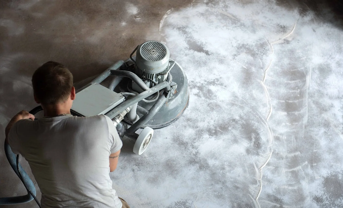 Construction worker in a family home living room that grind the concrete surface before applying epoxy flooring.Polyurethane and epoxy flooring.Concrete grinding.