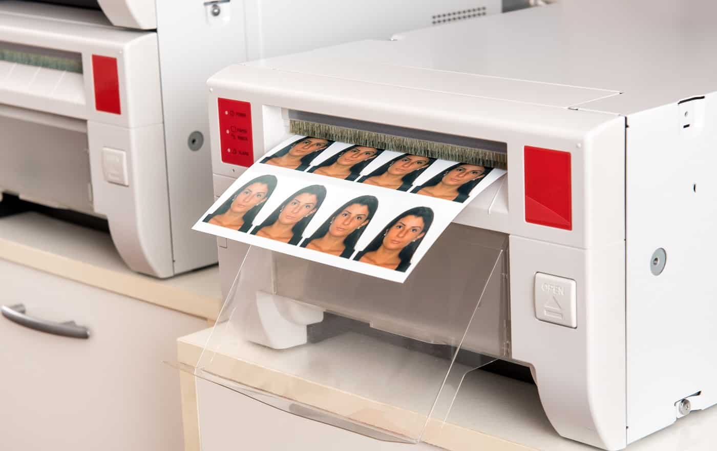 Printing passport photos of a woman on a printer with a sheet of eight photographs exiting the machine in a close up view