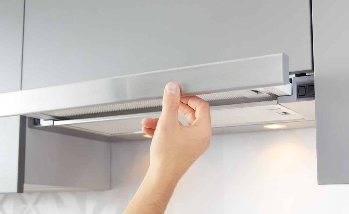 Man's hand opens kitchen hood for cooking or replacing filter.