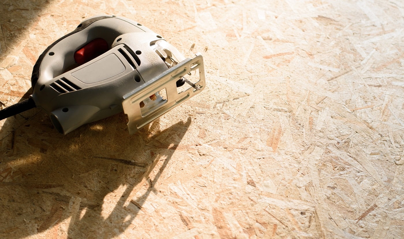 the process of sawing plywood with an electric jigsaw, a man holds a tool in his hand