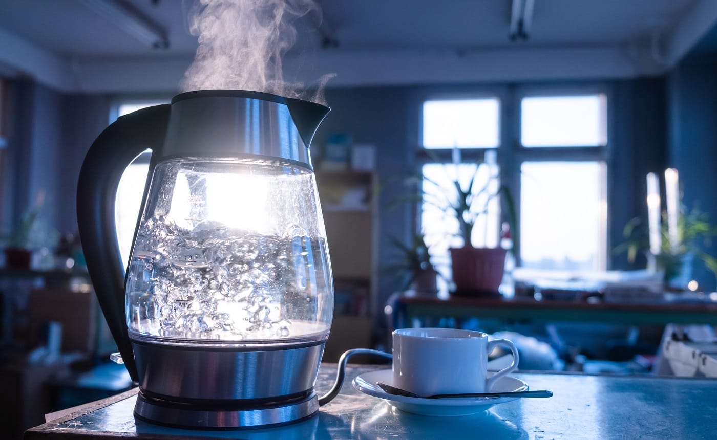 A transparent kettle of water boils against the background of the sunset shining through the window. The concept of coffee break and end of the working day. Electric Kettles Without Plastic Buying Guide